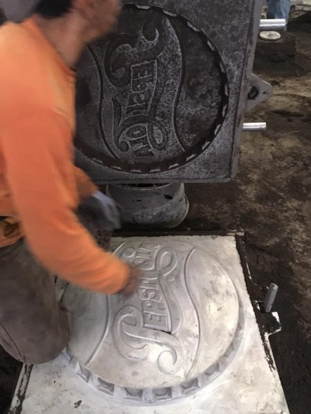 An open mold beside a metal casting with raised lettering during manufacturing